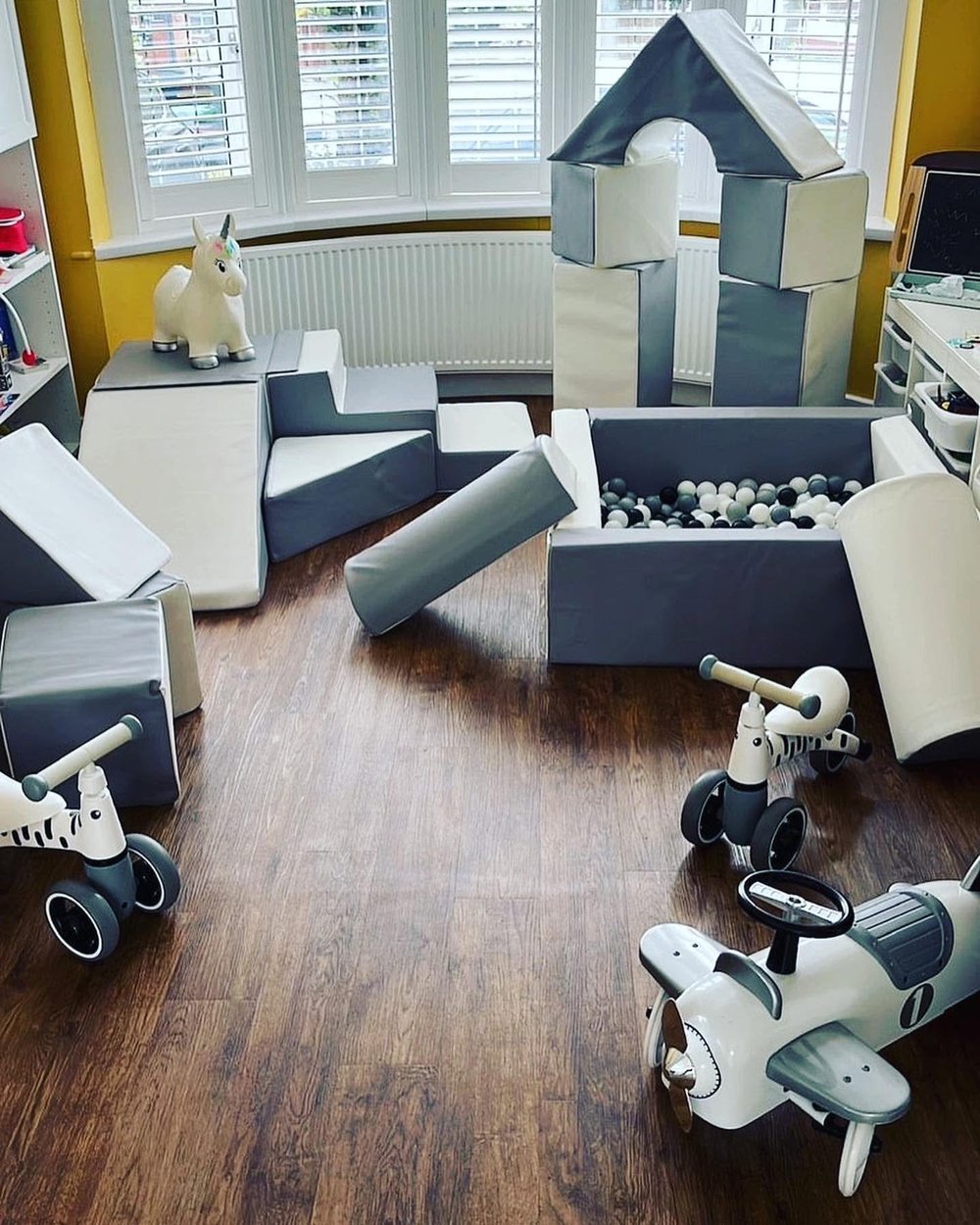 Grey and white soft play with castle tower, ball pit and ride-on toys